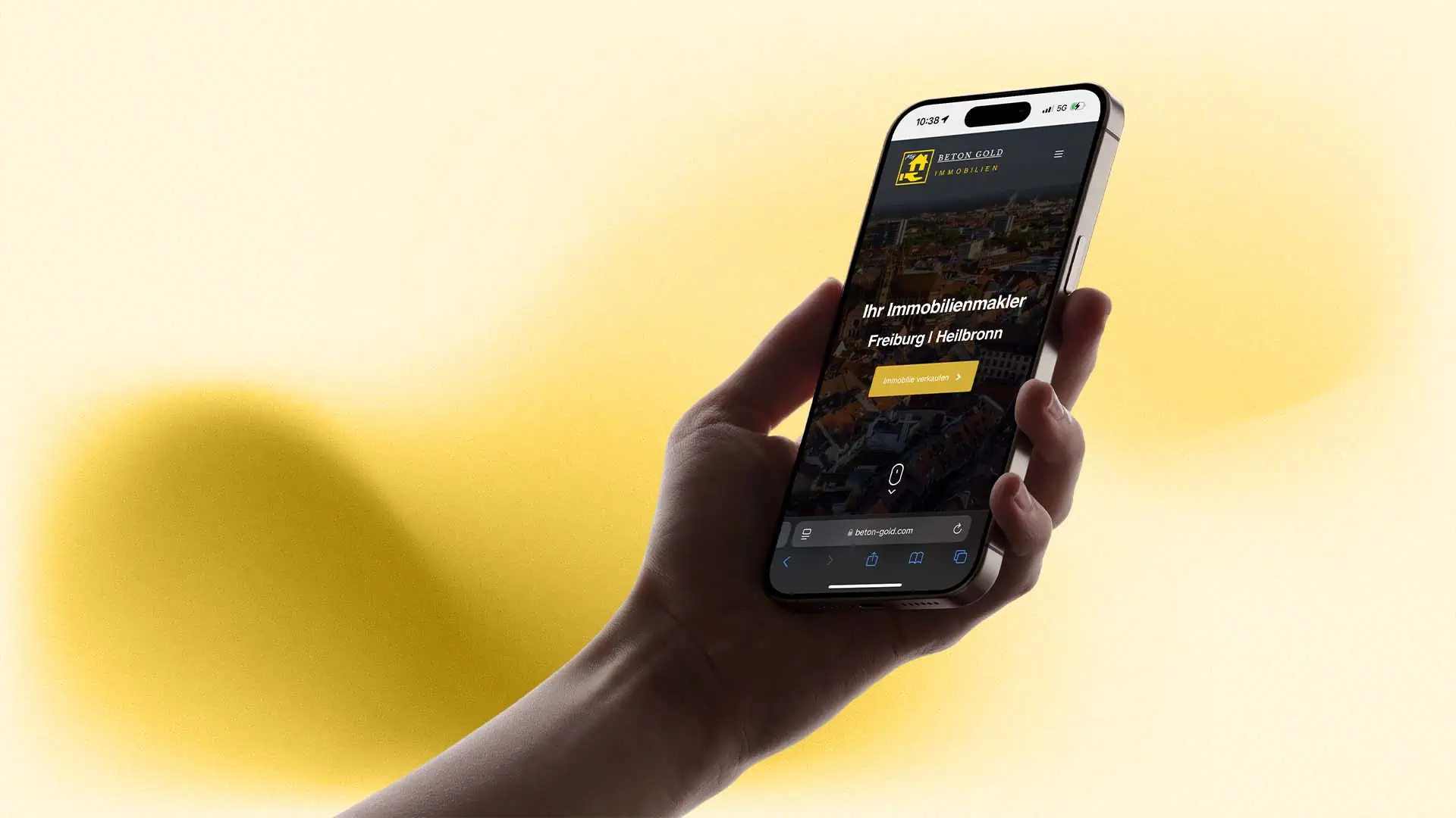 Hand hält ein Smartphone, auf dem die mobile Website von Betongold Immobilien mit der Headline Ihr Immobilienmakler Freiburg Heilbronn geöffnet ist.